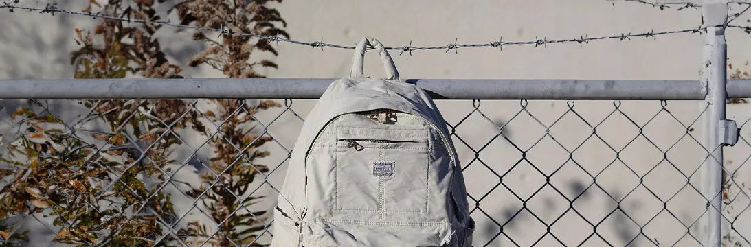 Porter-Yoshida & Co:  Backpack Hanging on Metal Fence