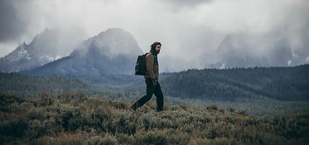 Man Walking Across Alaskan Wilderness Wearing Filson Outdoor Clothing an Backpack