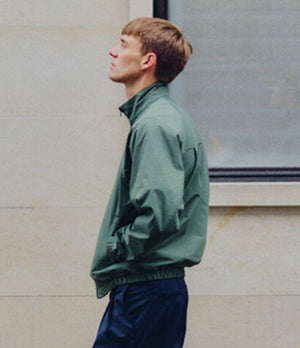 Man wearing a green Norse Projects jacket, showcasing minimalist Scandinavian design and functional outerwear style.