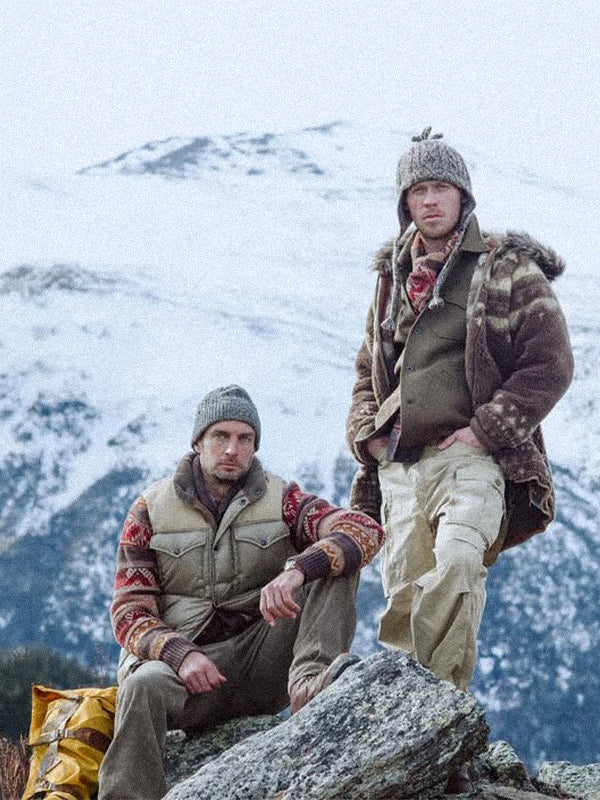 Two people in RRL by Ralph Lauren winter clothing sitting on a rock with a snowy mountain background
