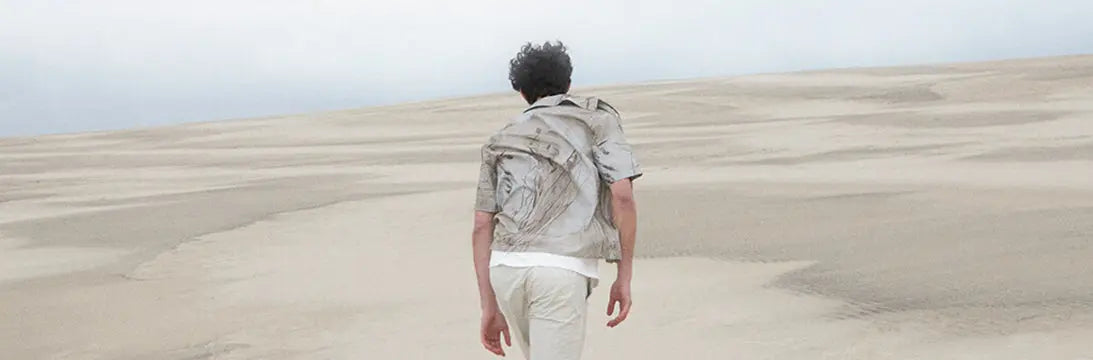Man Wearing Norse Projects Clothing Walking Across a Nordic landscape