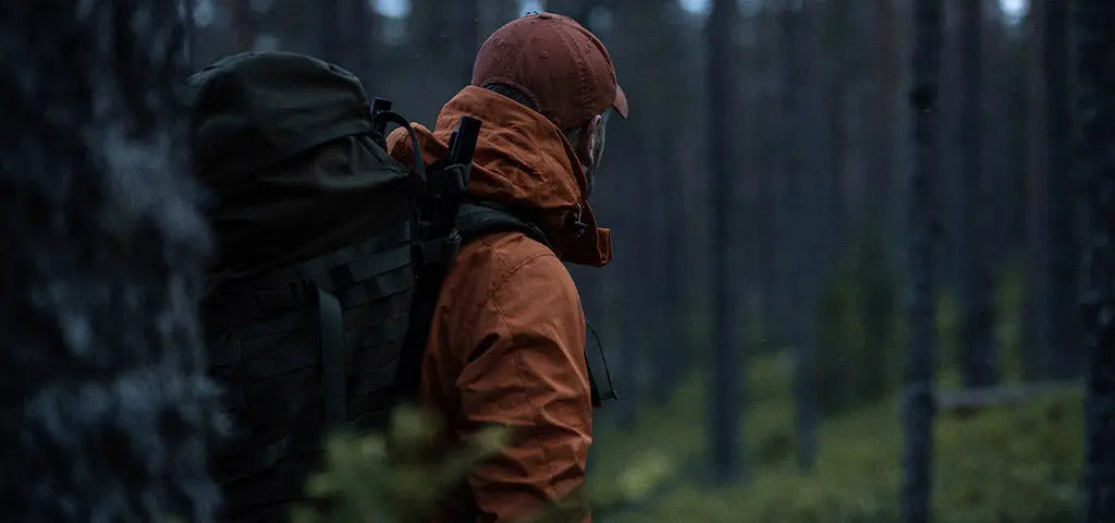 Man Standing in Forest Wearing Waterproof Sasta Jacket and Backpack